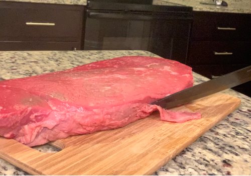 Knife removing surface fat from a lean cut of beef