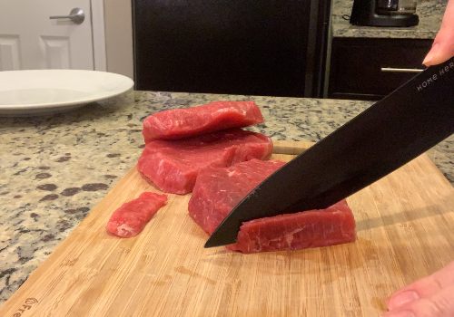 Firm beef being sliced into narrow strips