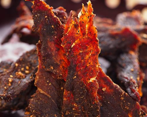 Close-up of thin jerky strips with red seasoning