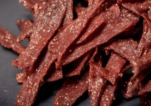 A pile of glossy, dark dried meat strips