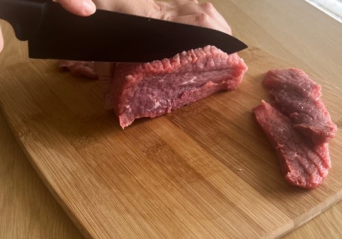 Beef being cut into short slices on a board