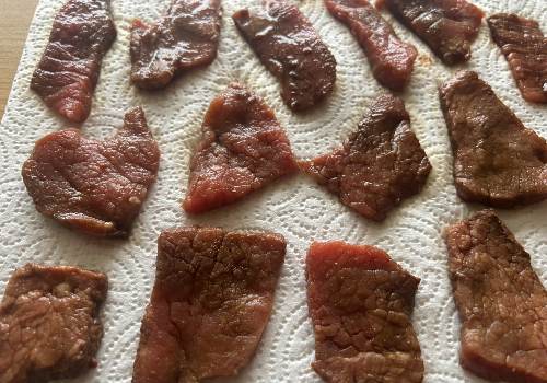 Seasoned beef pieces draining on paper towels