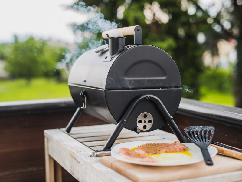 A small black smoker on a wooden outdoor counter