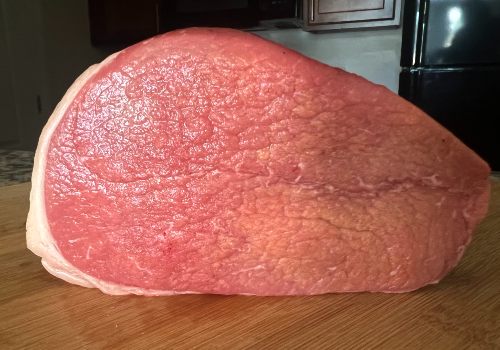 A large eye of round roast on a cutting board