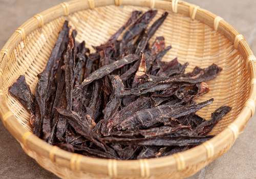 Narrow strips of dried meat in a shallow woven basket