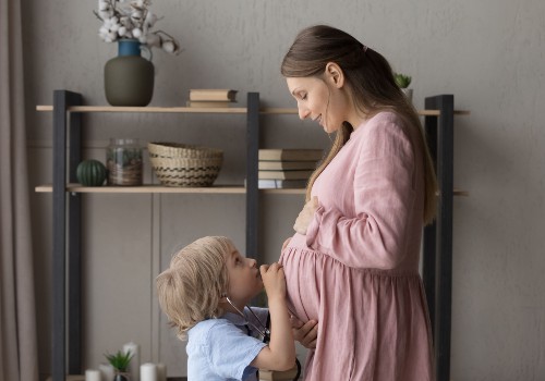 A child leaning close to a baby bump