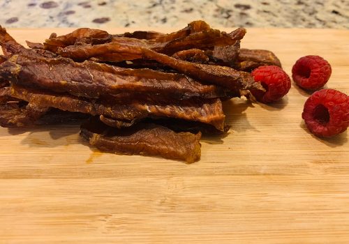Hot and sweet pork jerky piled beside raspberries