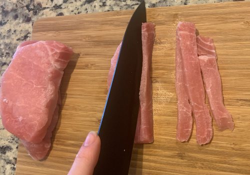 A pork chop being sliced into thin, straight strips