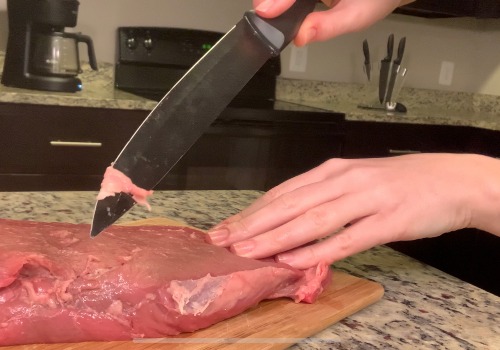 A cook trimming fat from raw beef