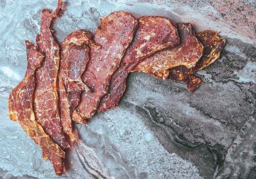 Thin cured meat slices on gray parchment