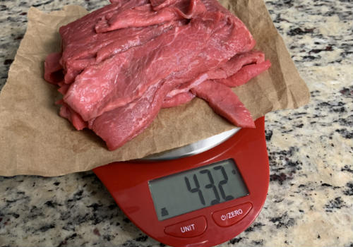 Raw beef strips on a scale reading 432 grams