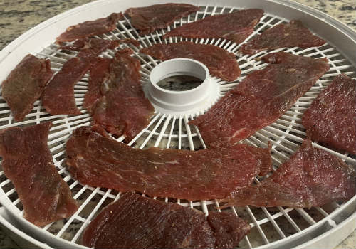 Broad marinated beef slices on a round dehydrator tray