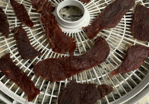 Dark teriyaki jerky pieces with curled edges on a tray