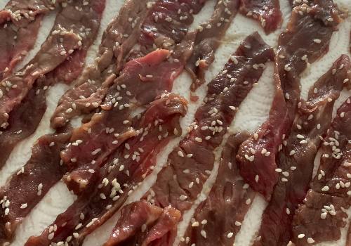 Sesame-coated marinated beef strips on paper towels