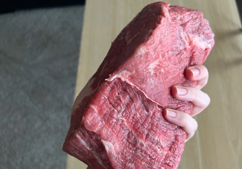 A hand holding a large bottom round roast