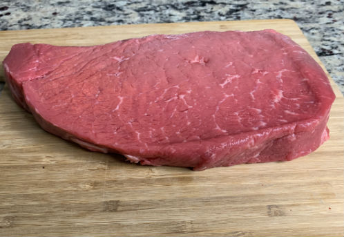 Top round London broil on a wooden cutting board