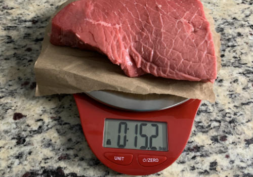 Raw beef on a scale showing 15.2 ounces