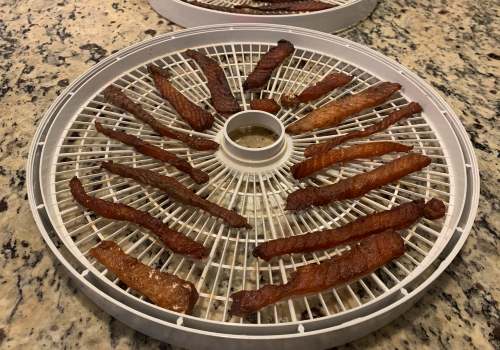 Darkened salmon jerky strips on a dehydrator tray
