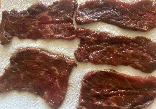 Marinated beef slices draining on paper towels