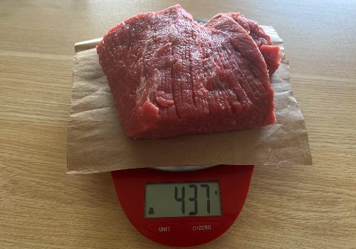Raw beef on a scale reading 437 grams