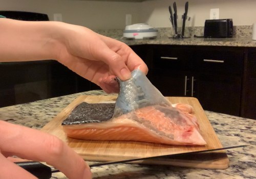 A cook lifting the skin away from a salmon fillet