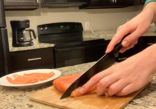 Salmon being sliced into thin strips on a wooden board
