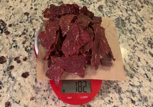 Finished beef jerky on a digital scale reading 182 grams