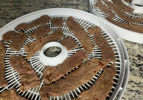 Marinated beef strips arranged on round dehydrator trays