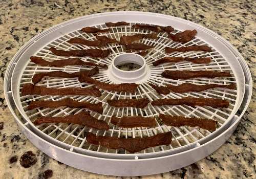 Dried pork jerky on a dehydrator tray