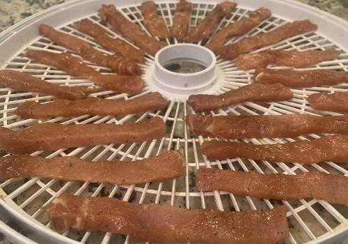 Marinated pork strips on a round dehydrator tray