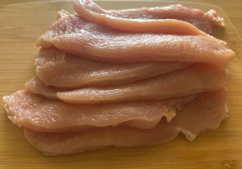 Thin raw turkey cutlets stacked on a cutting board