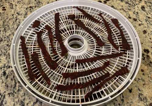 Darkened beef jerky on a dehydrator tray