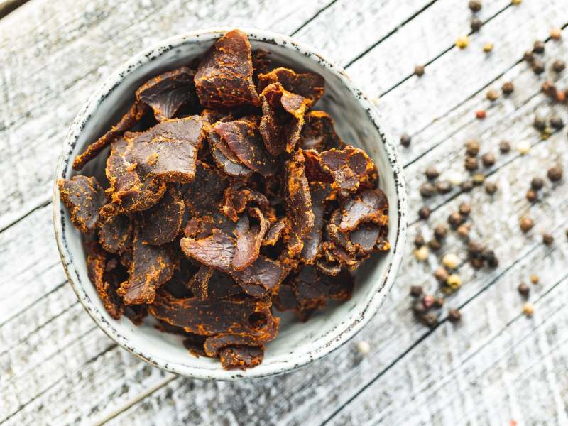 Sliced beef jerky in a bowl on a wooden surface